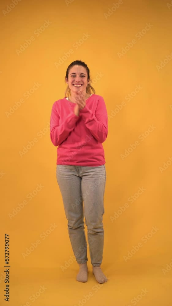 Vertical. Young girl clapping and smiling enthusiastically at a conference on isolated background. Yellow screen with chroma key. Cheerful blonde woman applauding and celebrating a success. Vertical. Young girl clapping and smiling enthusiastically at a conference on isolated background. Yellow screen with chroma key. Cheerful blonde woman applauding and celebrating a success.