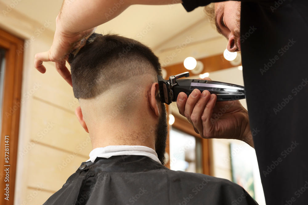 Naklejka premium Professional hairdresser working with client in barbershop, closeup