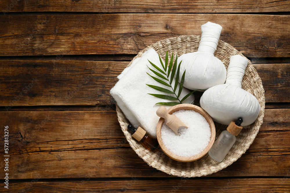 Composition with herbal massage bags and other spa products on wooden table, top view. Space for text Composition with herbal massage bags and other spa products on wooden table, top view. Space for text