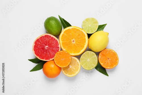 Different citrus fruits with fresh leaves on white background, top view