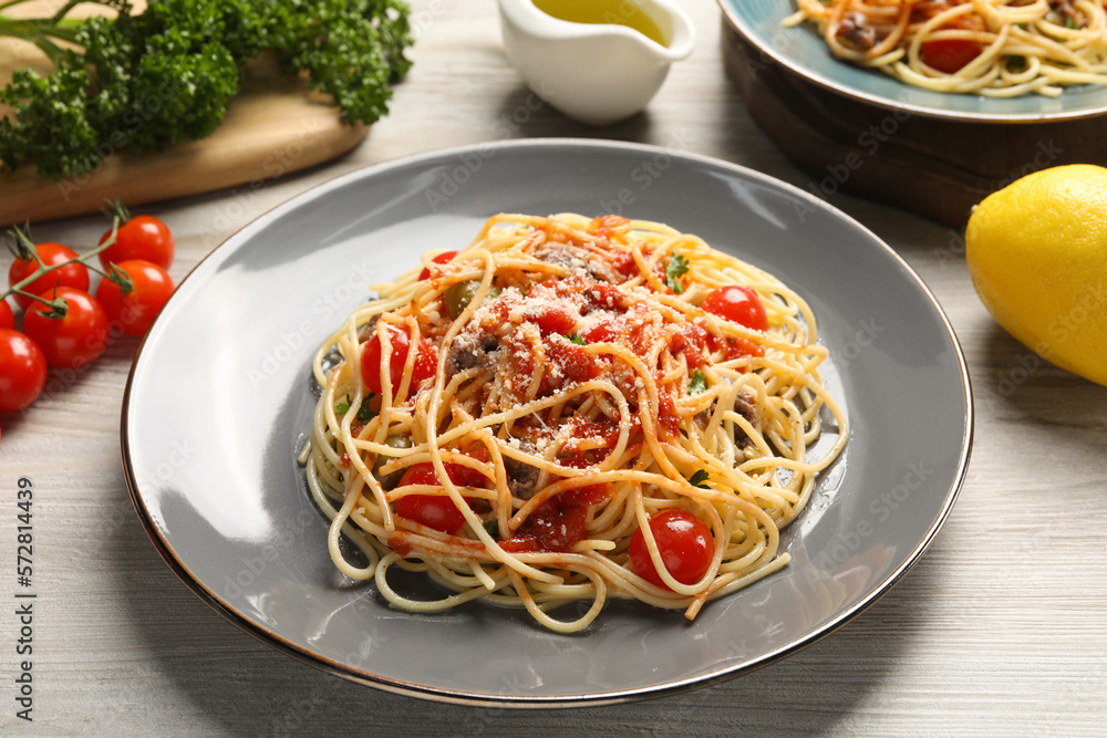 Delicious pasta with anchovies, tomatoes and parmesan cheese on white wooden table Delicious pasta with anchovies, tomatoes and parmesan cheese on white wooden table