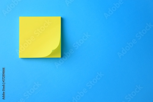 Blank paper note on light blue background, top view. Space for text