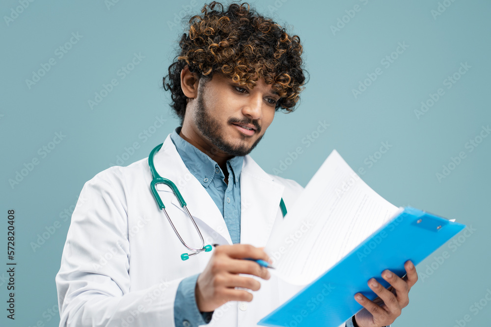 Indian male doctor with stethoscope, examines the patient's medical history, blue background Indian male doctor with stethoscope, examines the patient's medical history, blue background