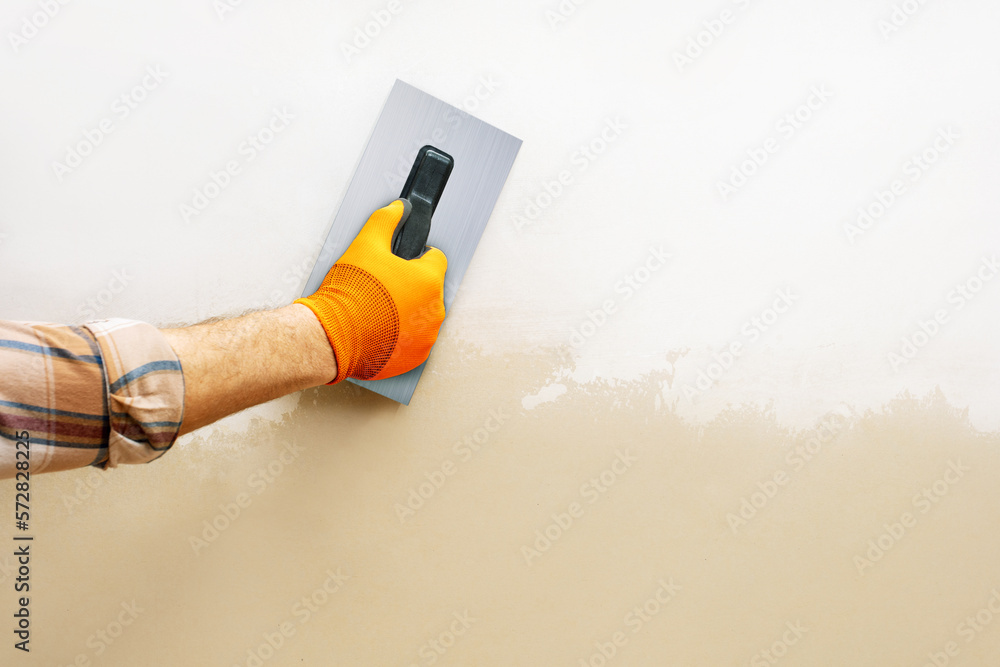 Φωτογραφία male hand using spatula and working  plastering on wall