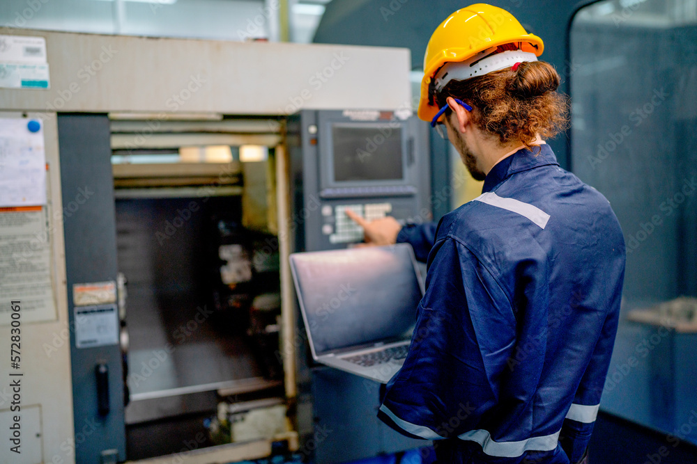 Back of engineer or technician worker press button of big machine also hold laptop during work in factory workplace. Back of engineer or technician worker press button of big machine also hold laptop during work in factory workplace.