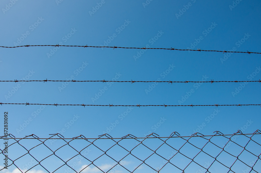 barbed wire fence with blue sky as background barbed wire fence with blue sky as background