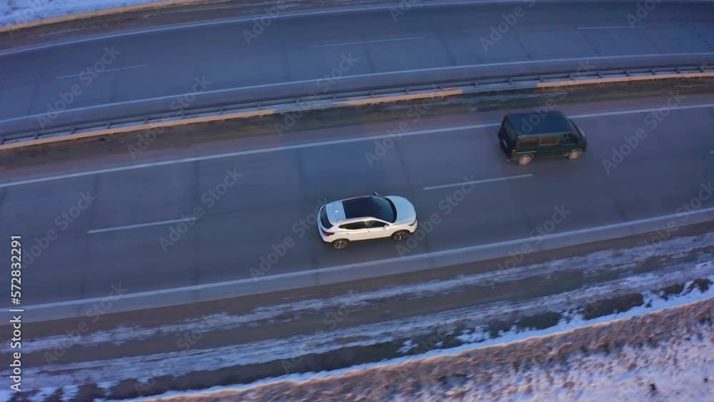 Top view of the roof of a white car passing on a road with snow on the side of the road