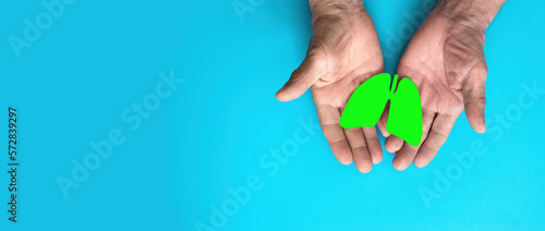 hands of a pensioner hold a symbol of the lungs on a blue background. copyspace, banner.bronchial asthma and allergies, healthy lungs in old age, bronchitis, covid epidemic. clean air, stay healthy