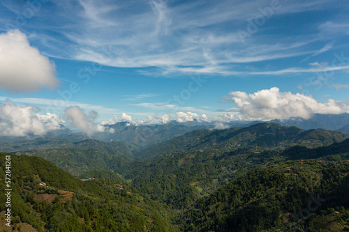 Aerial view of Mountains covered rainforest, trees and blue sky with clouds. Philippines. © Alex Traveler