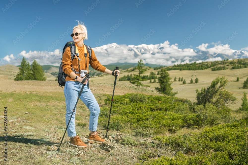 Portrait of a happy  smiling  woman hiker standing on the slope of mountain. Travel and active lifestyle concept.