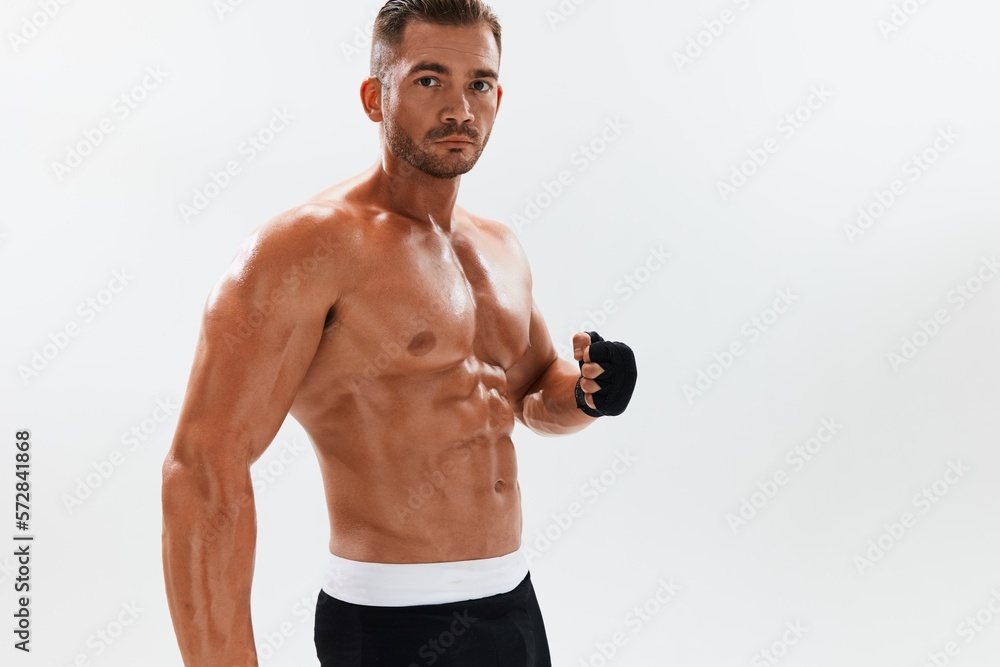 Man athletic bodybuilder poses in boxing gloves with nude torso abs in full-length background, boxing and martial arts. Advertising, sports, active lifestyle, competition, challenge concept. 