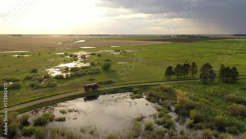 Aerial view of farmland in North Dakota, USA. American countryside, farming vehicles in the field. Sun reflection, glare in the water