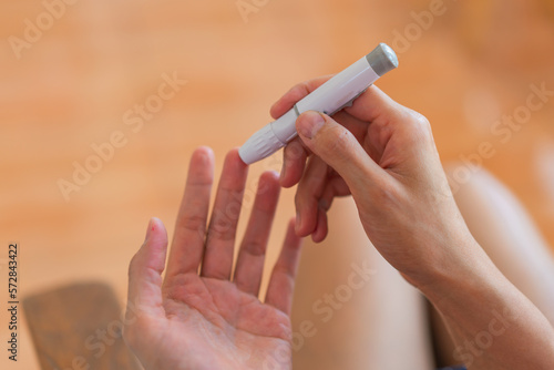 young woman using blood test kit at home while doing health check . home finger prick blood test . close up, diabetes concept, elderly health care,