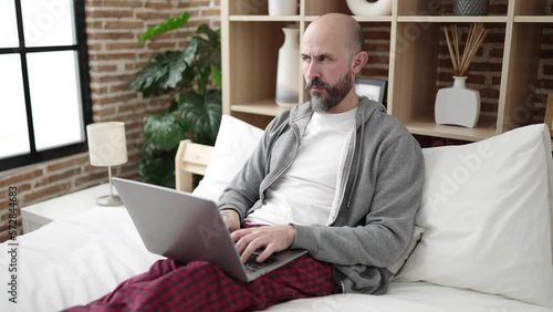 Wallpaper Mural Young bald man using laptop sitting on bed at bedroom Torontodigital.ca