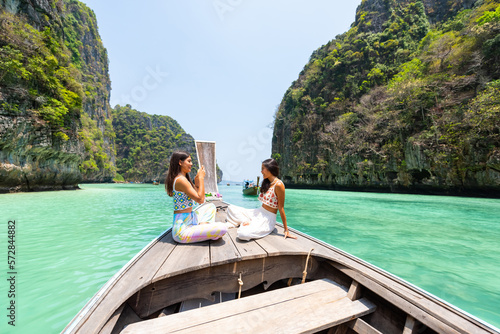 Asian woman friend using mobile phone taking selfie together during travel on boat passing island beach lagoon in sunny day. Attractive girl enjoy and fun outdoor lifestyle on summer holiday vacation
