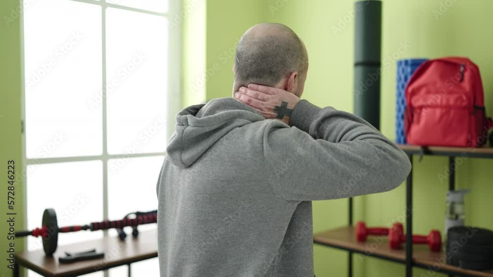 Young bald man suffering for cervical pain at sport center