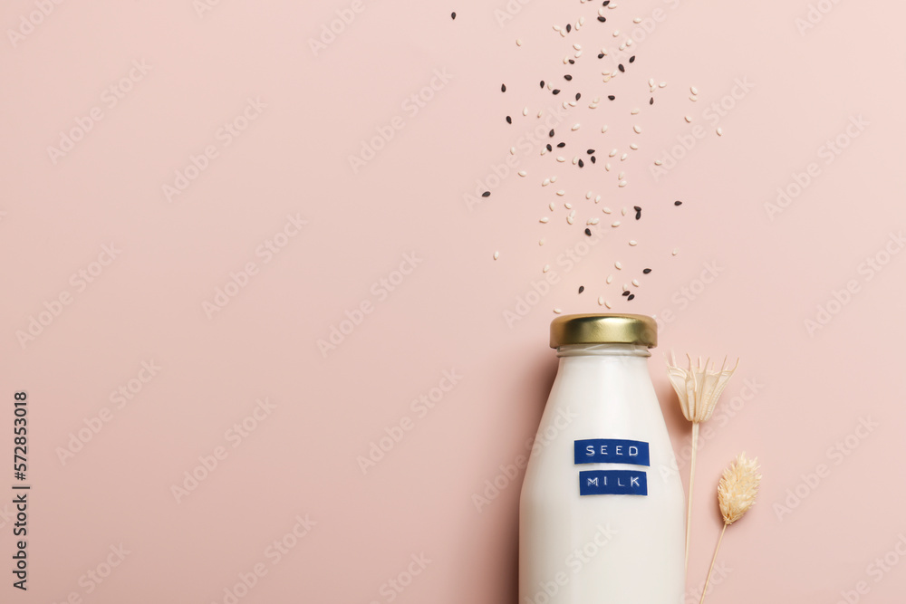 sesame seed milk in bottle on beige background with plant. copy space. Raw diet meal. Healthy vegetarian food and lifestyle.eco friendly product