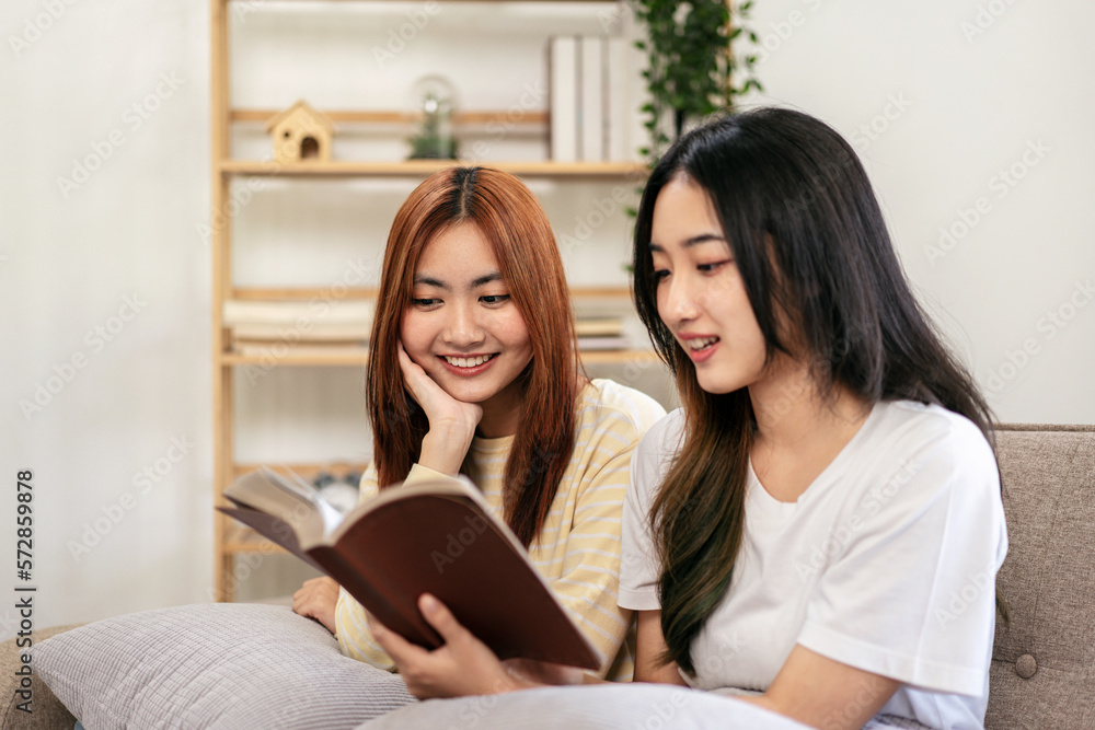 Young woman lesbian couple reading a book together while sitting Young woman lesbian couple reading a book together while sitting