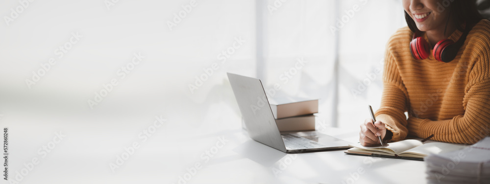 Asian teenage woman sitting in white office with laptop, she is a student studying online with laptop at home, university student studying online, online web education concept. - obrazy, fototapety, plakaty 