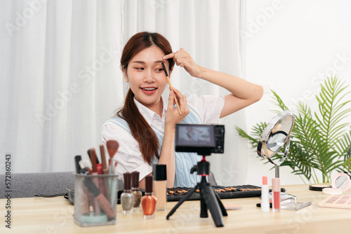 Young beauty influencer using brush with eyebrow to testing and