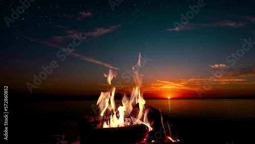 bonfire burns at night against the background of mountains and sea with bright stars photo