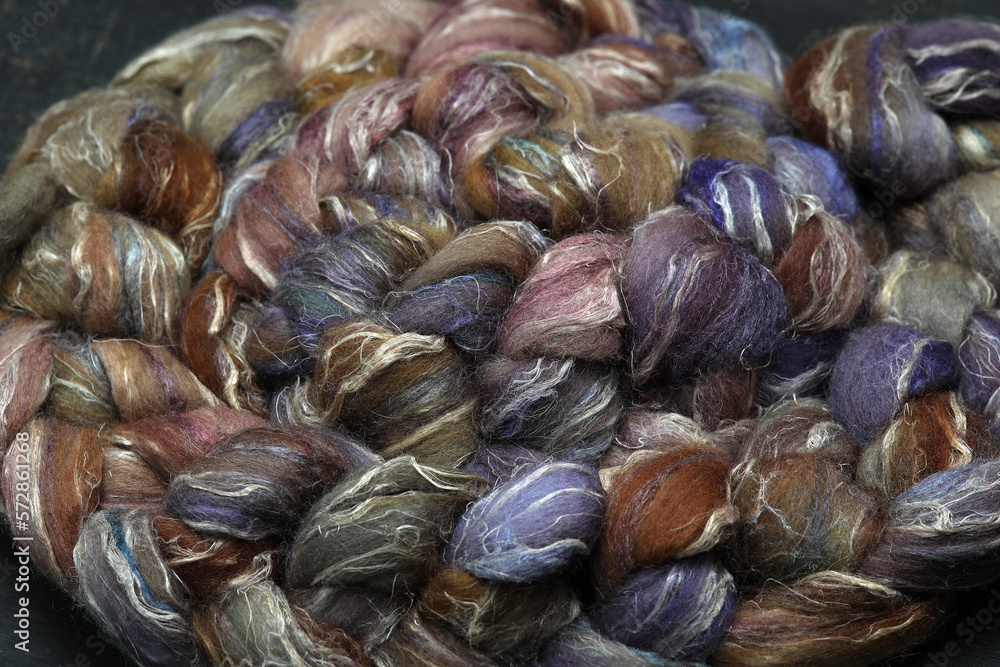 Colorful, handdyed roving of sheepwool, braid and rolled up, natural material ready for spinning on a traditional spinning wheel as a hobby. Colorful, handdyed roving of sheepwool, braid and rolled up, natural material ready for spinning on a traditional spinning wheel as a hobby.