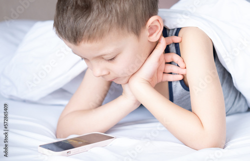 beautiful cute 6 year old boy with smartphone in bed.