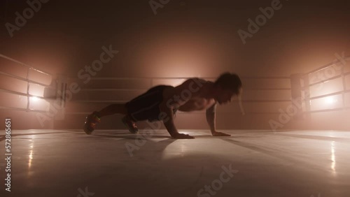 Portrait of a male athlete boosting his stamina and endurance while preparing for a sparring. Close-up view of professional boxer performing pushups and clapping in the air. High quality 4k footage photo