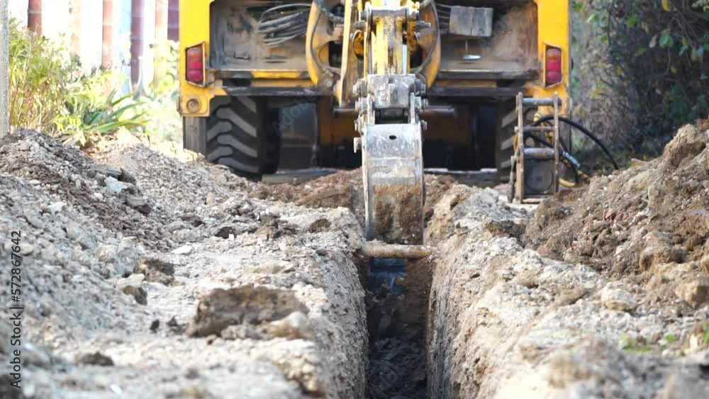 Excavator digs a trench to lay pipes. Close up of an excavator digging a deep trench. An excavator digs a trench in the countryside to lay a water pipe. Slow motion Excavator digs a trench to lay pipes. Close up of an excavator digging a deep trench. An excavator digs a trench in the countryside to lay a water pipe. Slow motion