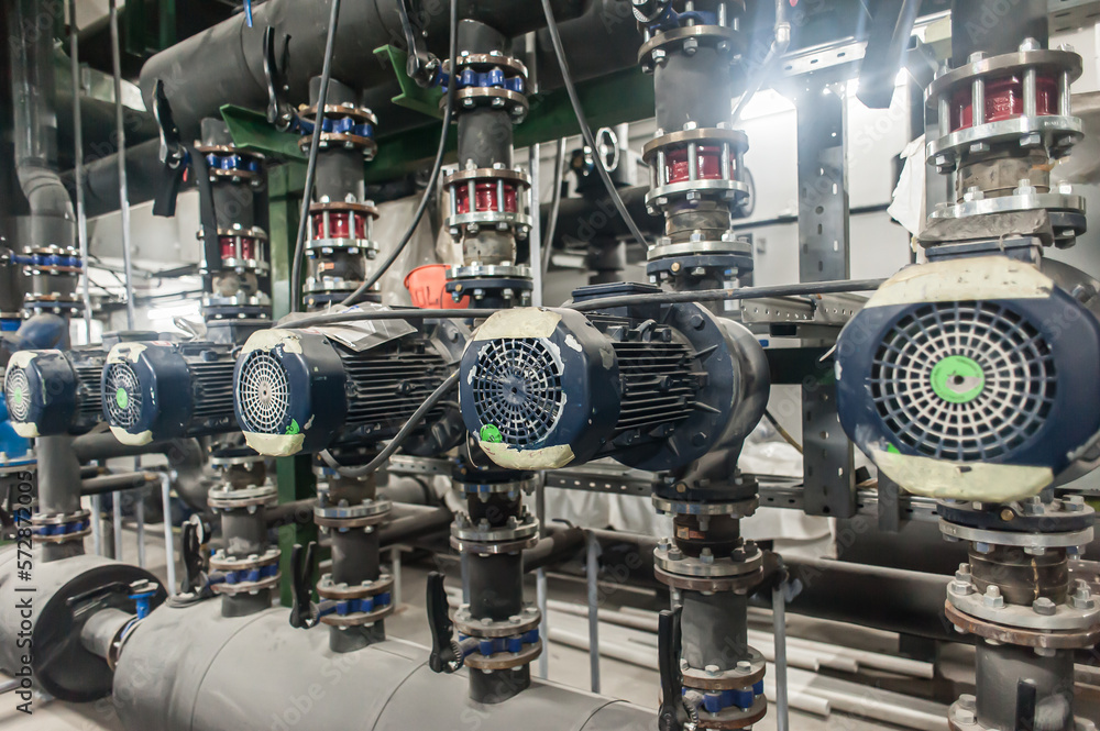 Huge industrial water pump and air handling unit in the ventilation plant room with ductworks and insulated pipelines Huge industrial water pump and air handling unit in the ventilation plant room with ductworks and insulated pipelines