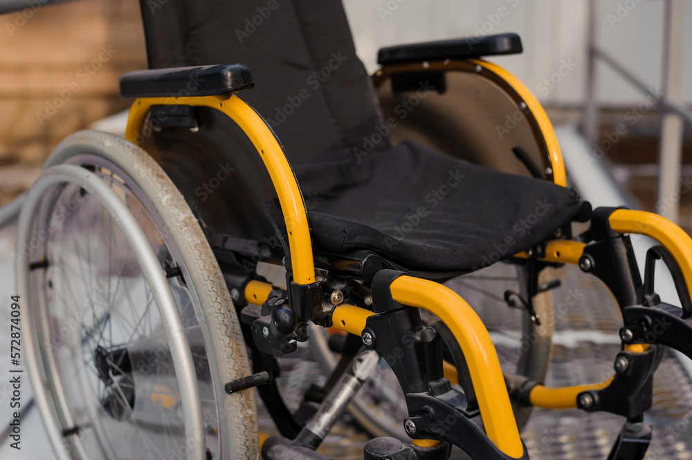 Empty wheelchair in the hospital on the ramp. Wheelchair close-up. Children's wheelchair Empty wheelchair in the hospital on the ramp. Wheelchair close-up. Children's wheelchair