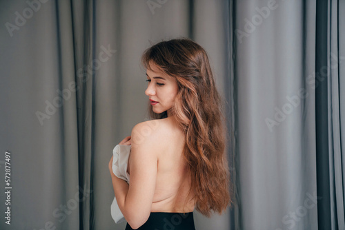 view from the back. an attractive slender young woman topless in black leggings.