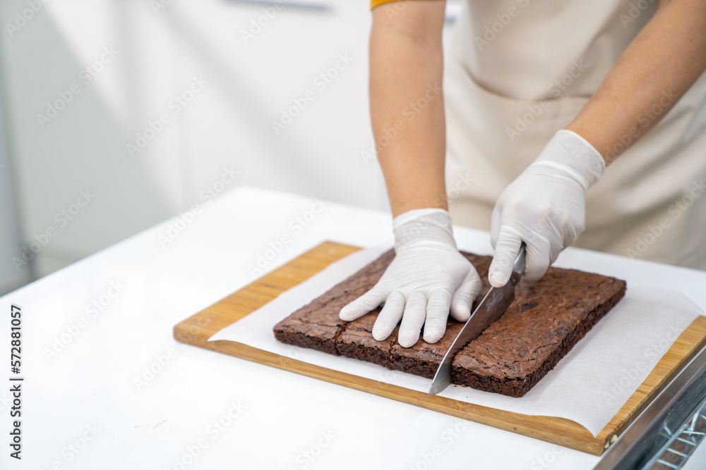 Asian man bakery chef cut chocolate brownie on cutting board in the