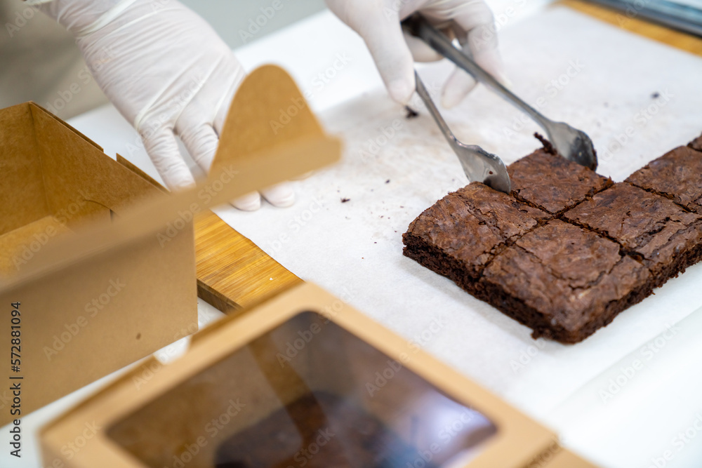Asian man bakery shop owner packing chocolate brownie for customer