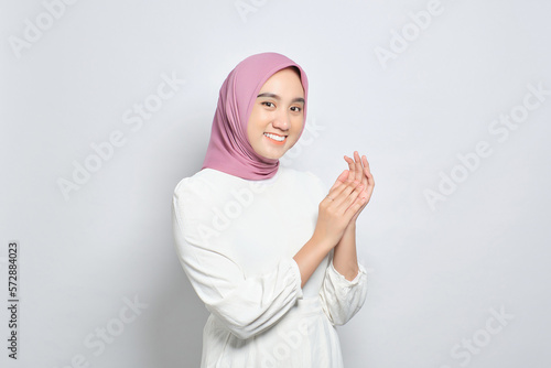 Smiling young Asian Muslim woman clapping hands, celebrating success with happy facial expressions isolated over white background