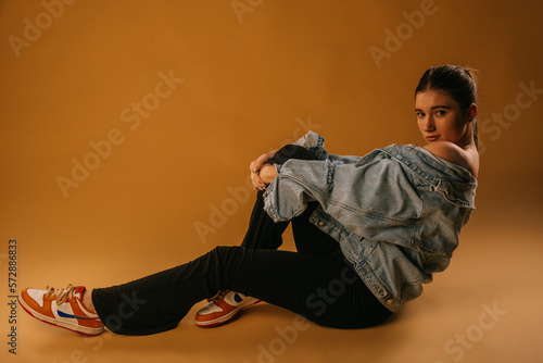 Fashion girl in studio sitting on a beige background