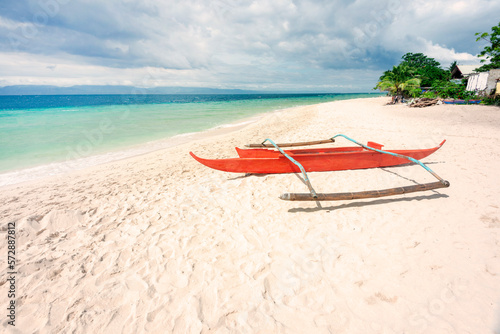 Red,Philippine style fishing canoe at White Beach,Moalboal,Cebu Island,Philippines.