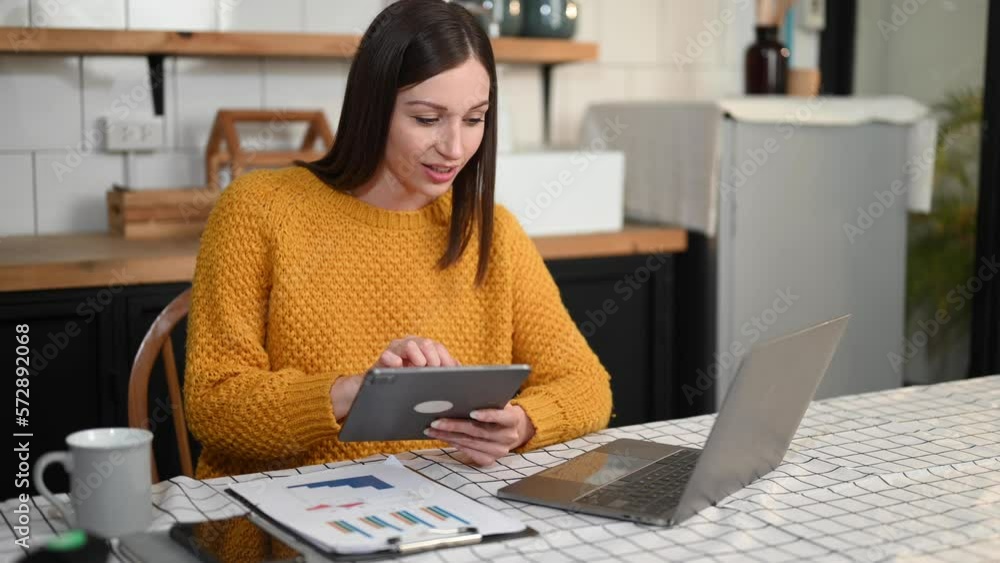 Beautiful woman using laptop and tablet while sitting at her working place. Concentrated at home Beautiful woman using laptop and tablet while sitting at her working place. Concentrated at home