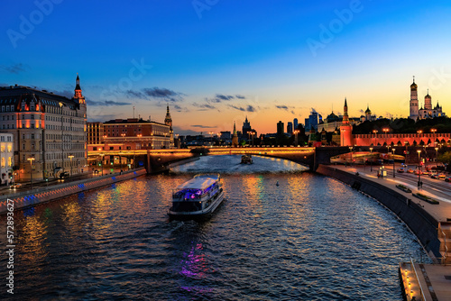 cityscape of Moscow river scenery. Tourboat sails on the river in evening. Moscow Kremlin and Sofiyskaya embankment at night photo