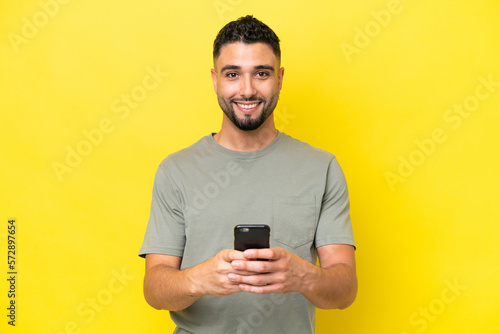 Young Arab handsome man isolated on yellow background sending a message with the mobile