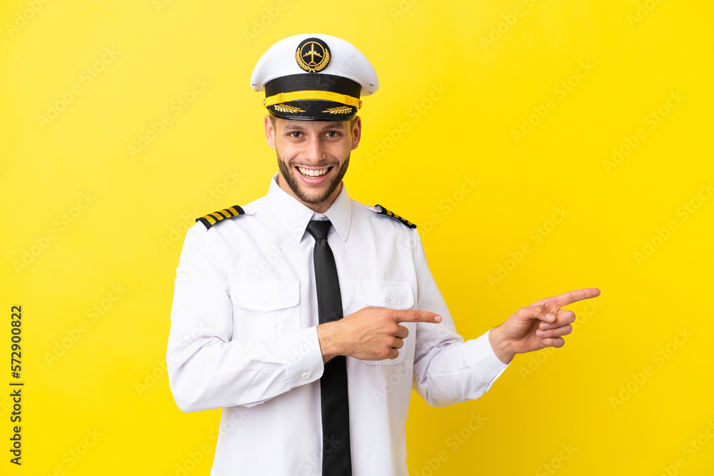 Airplane caucasian pilot isolated on yellow background surprised and pointing side