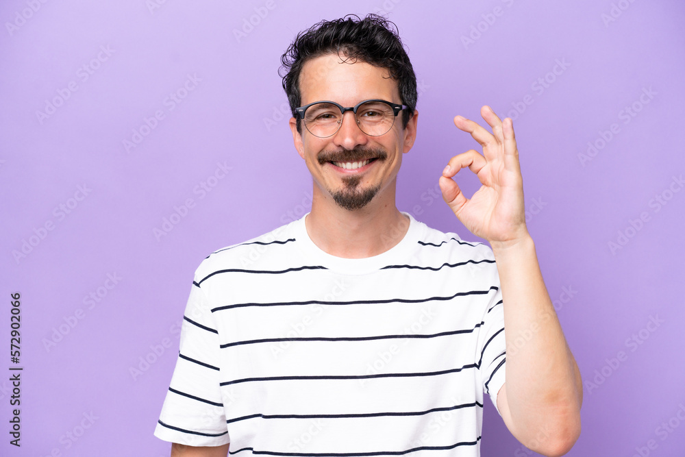 Young caucasian man isolated on purple background With glasses and doing OK sign Young caucasian man isolated on purple background With glasses and doing OK sign