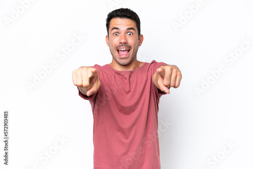 Young handsome man over isolated white background surprised and pointing front