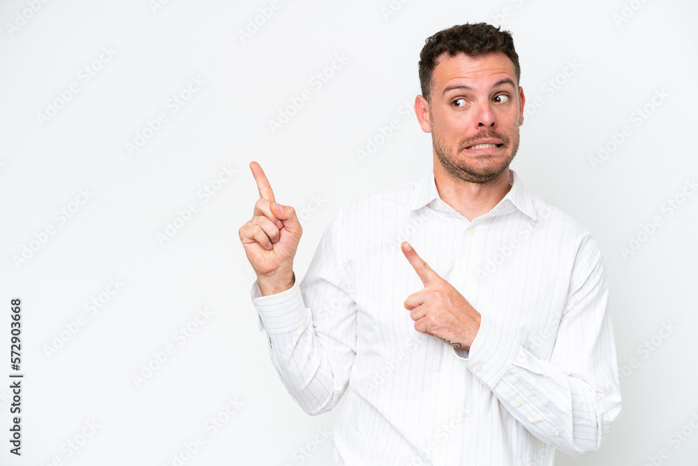 Young caucasian handsome man isolated on white background frightened and pointing to the side Young caucasian handsome man isolated on white background frightened and pointing to the side