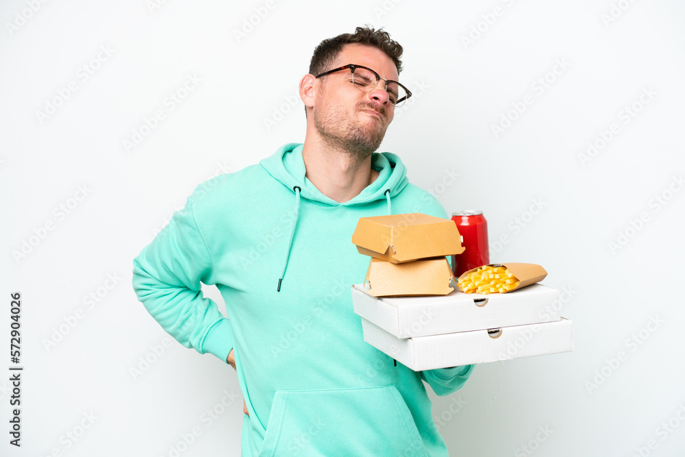 Young caucasian man holding fast food isolated on white background suffering from backache for having made an effort Young caucasian man holding fast food isolated on white background suffering from backache for having made an effort