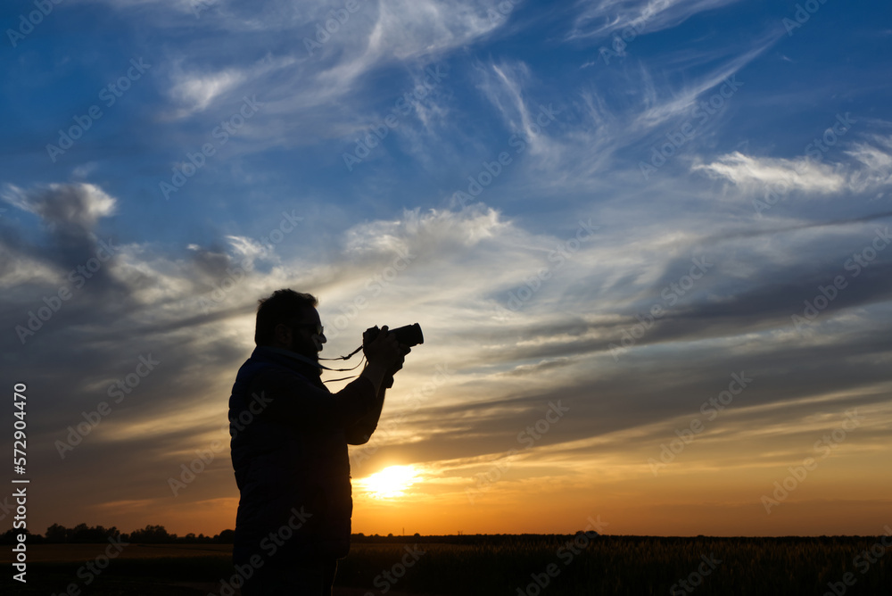 taking photos at sunset, silhouetted against the light under a spectacular sky