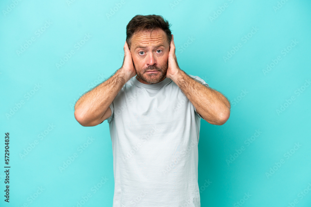 Middle age caucasian man isolated on blue background frustrated and covering ears Middle age caucasian man isolated on blue background frustrated and covering ears