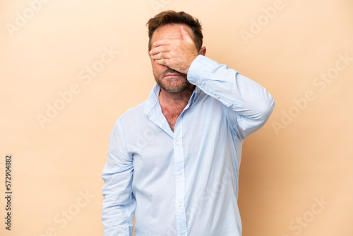 Middle age caucasian man isolated on beige background covering eyes by hands. Do not want to see something