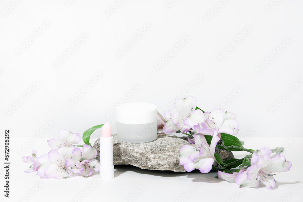 White cosmetics background. Cosmetic bottle containers with flowers plant . Blank label package for branding mock-up, with hard shadows. Natural organic beauty product concept. Banner