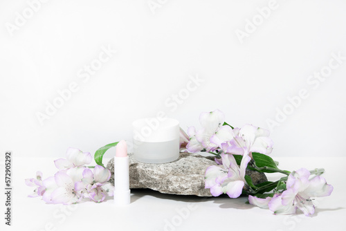 White cosmetics background. Cosmetic bottle containers with flowers plant . Blank label package for branding mock-up, with hard shadows. Natural organic beauty product concept. Banner